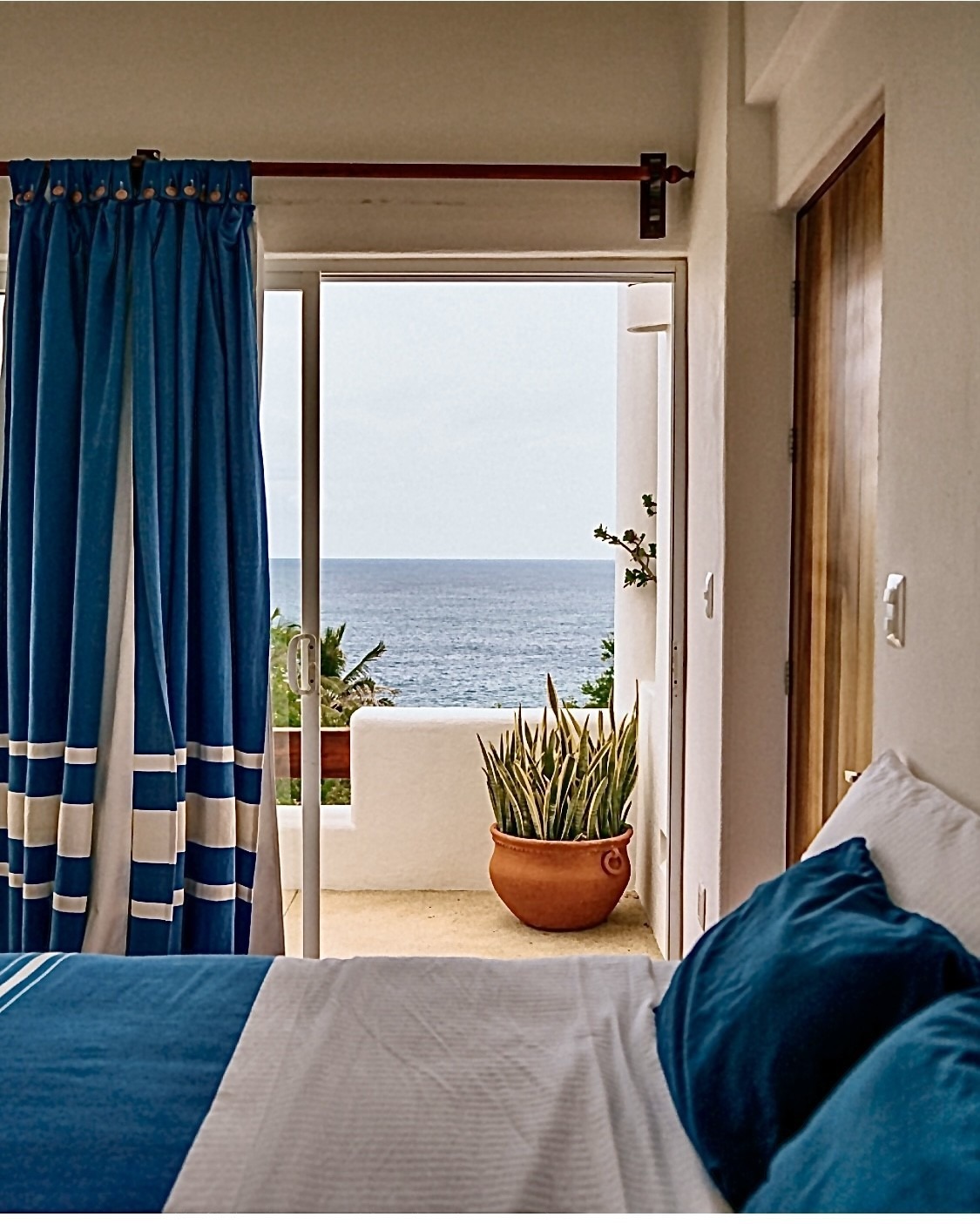 Cozy bedroom with blue curtains and bedding.