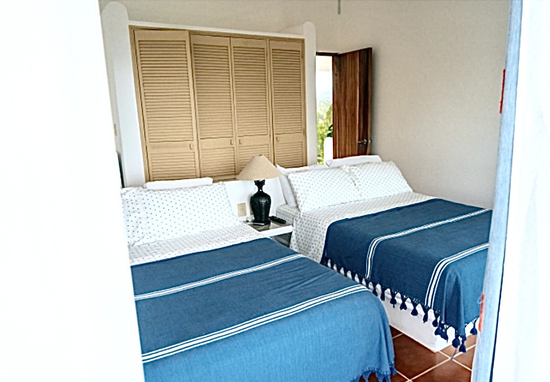 Two neatly made twin beds with blue throws and white pillows in a cozy bedroom.