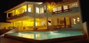 Modern luxury house with a lit swimming pool at night.