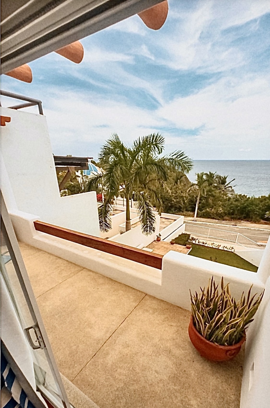 Ocean-view balcony with palm trees and modern white villa architecture.